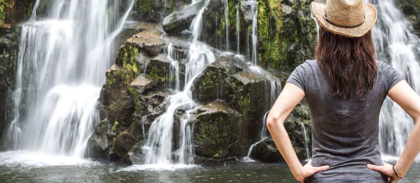 Woman-Wearing-Hat-and-Looking-at-Waterfall-New-Zealand-521997885_1352x590